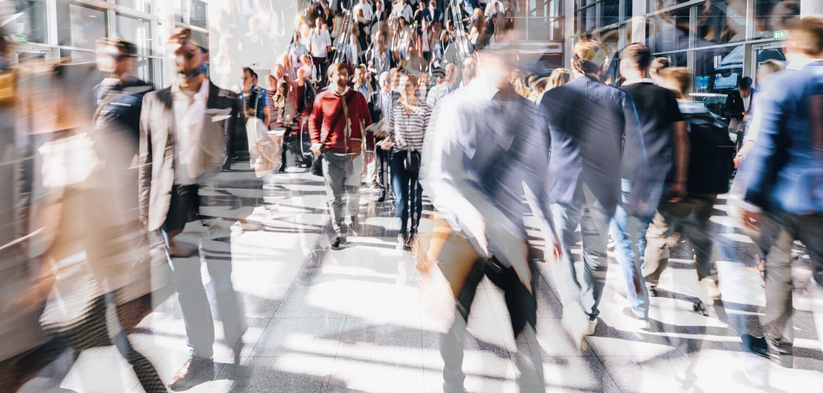 Drukke stationshal of passage met veel mensen die in verschillende richtingen lopen, waardoor een bewegingsonscherp en dynamisch beeld ontstaat